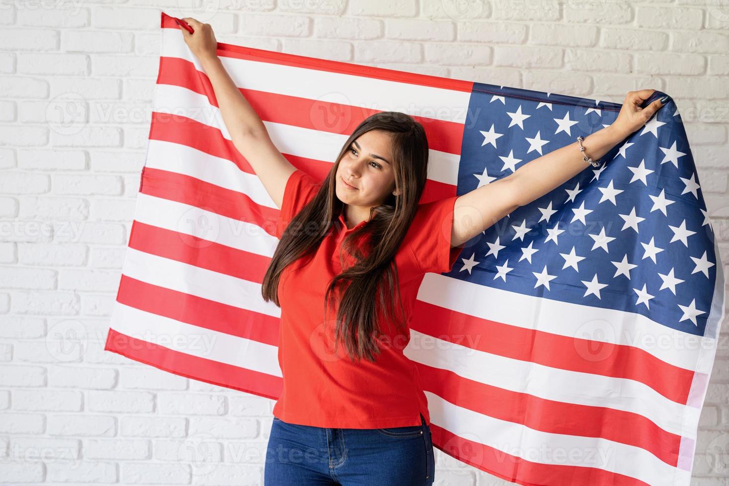 Beautiful young woman with American flag, arms outstretched photo