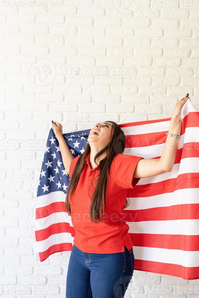 Beautiful young laughing woman with American flag, arms outstretched photo