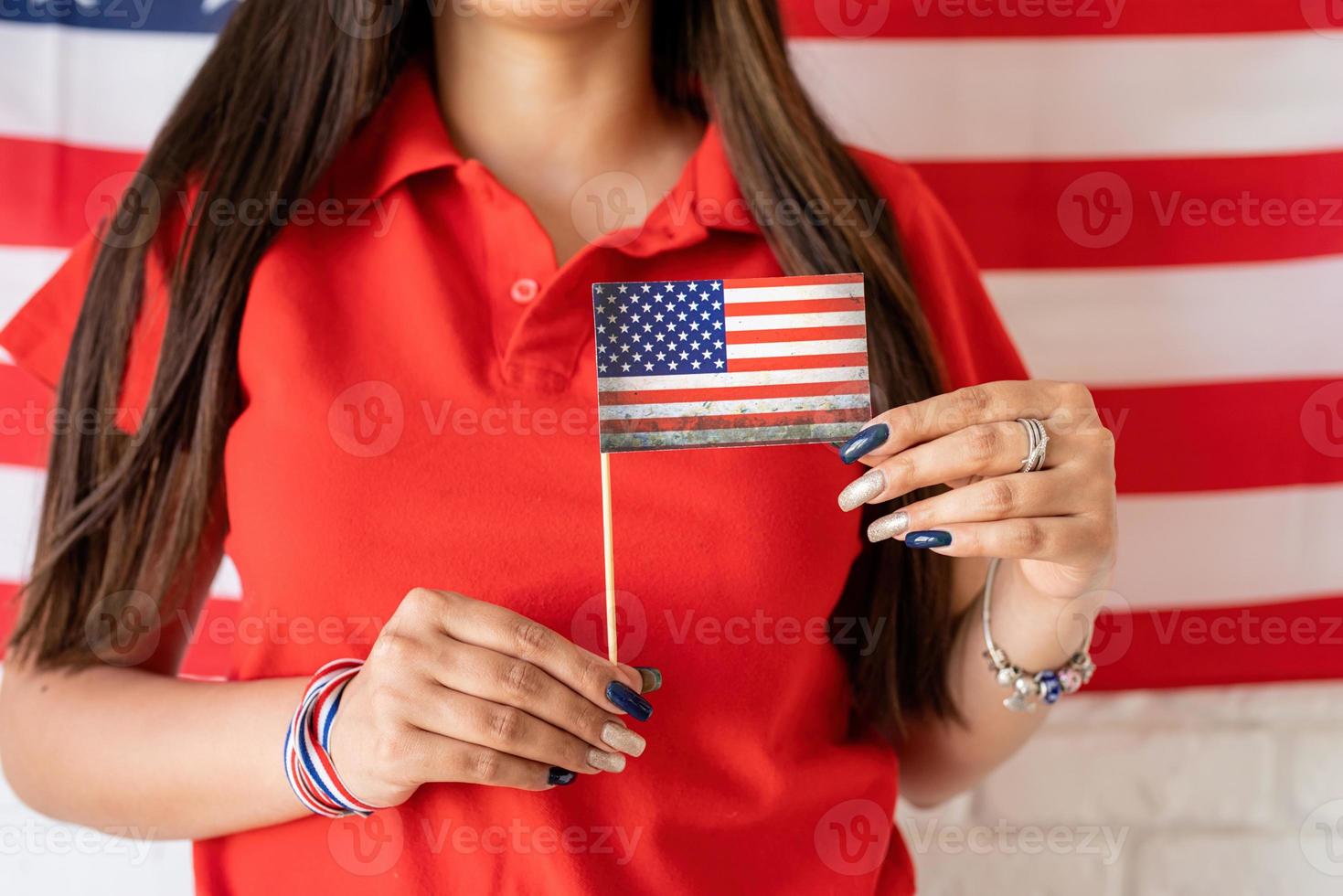 Mujer sosteniendo una pequeña bandera nacional en el fondo de la bandera de Estados Unidos foto