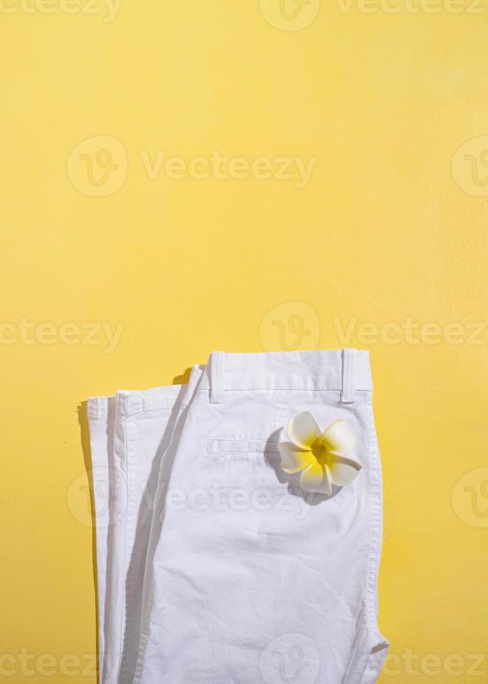 White summer jeans with plumeria flower on yellow background photo