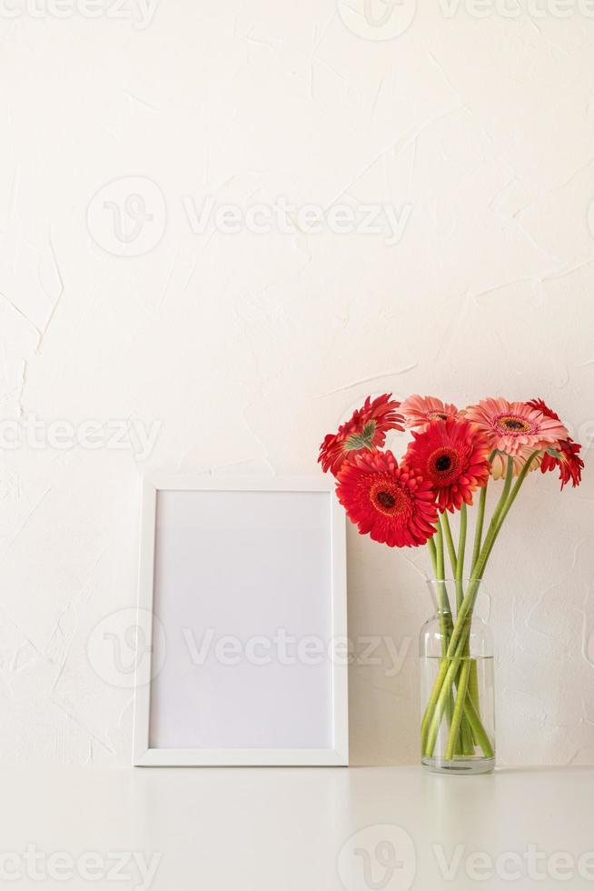 Red gerbera flowers with a blank white frame on white background photo