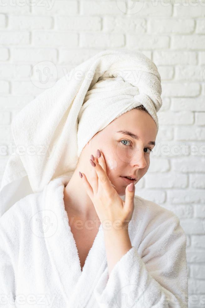 Woman applying face cream at home photo