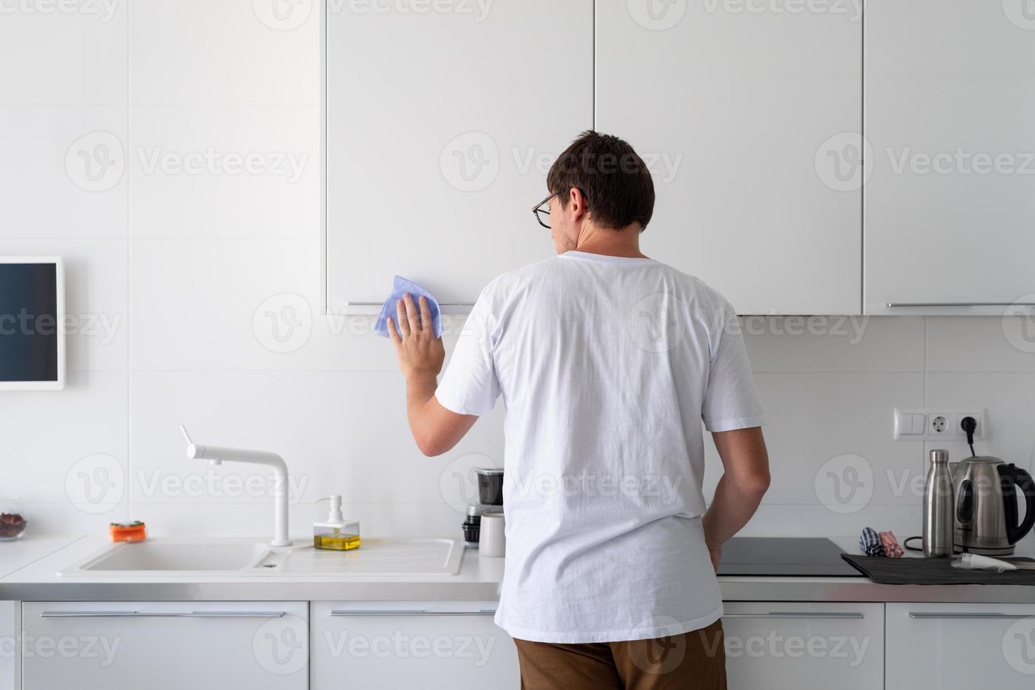 hombre limpiando las superficies de la cocina foto