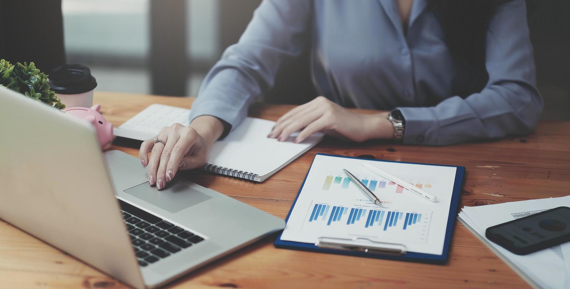 Businesswoman checking reported profits on the paper and laptop. photo