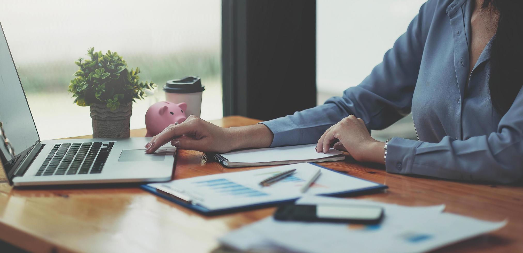 Businesswoman checking reported profits on the paper and laptop. photo