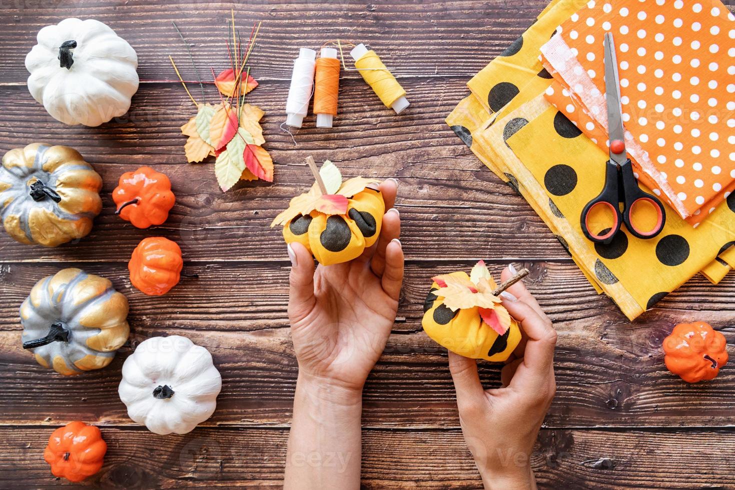 Manos de mujer sosteniendo calabazas textiles de halloween diy foto