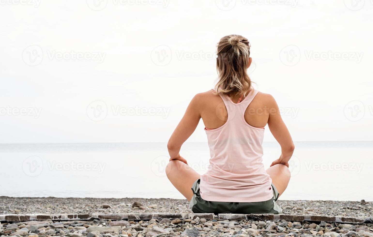mujer meditando en la orilla del mar foto