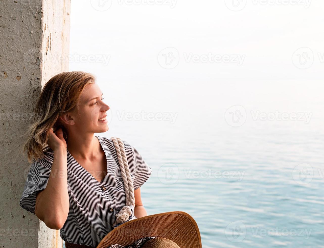 Portrait of a woman standing by the sea holding her summer hat photo