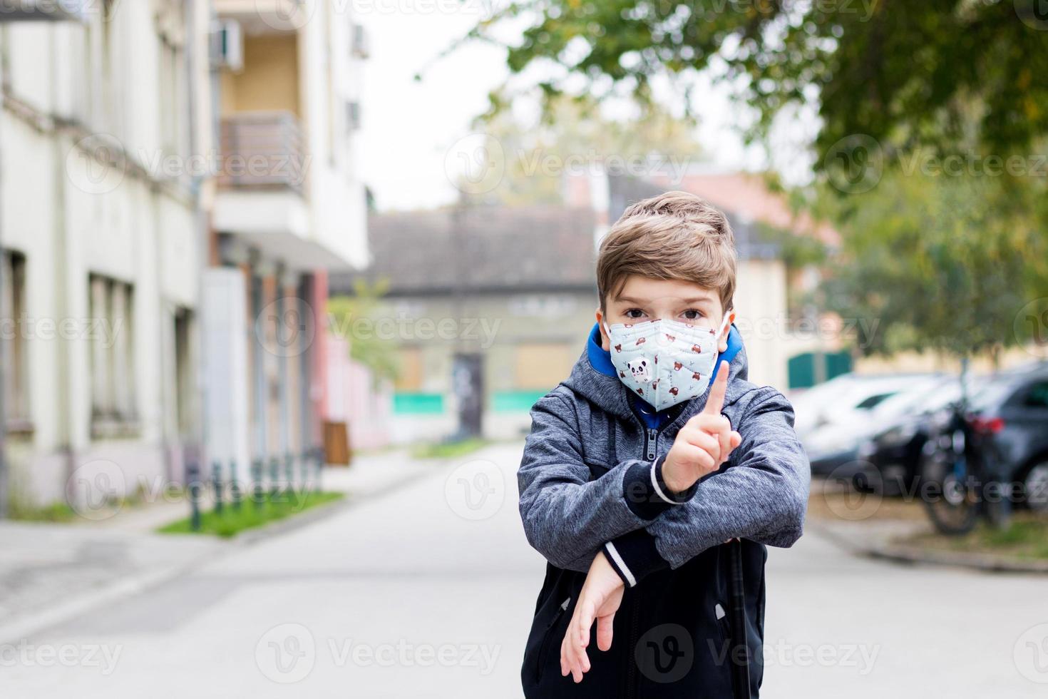 Little boy wears face mask outdoors due to coronavirus pandemic. photo