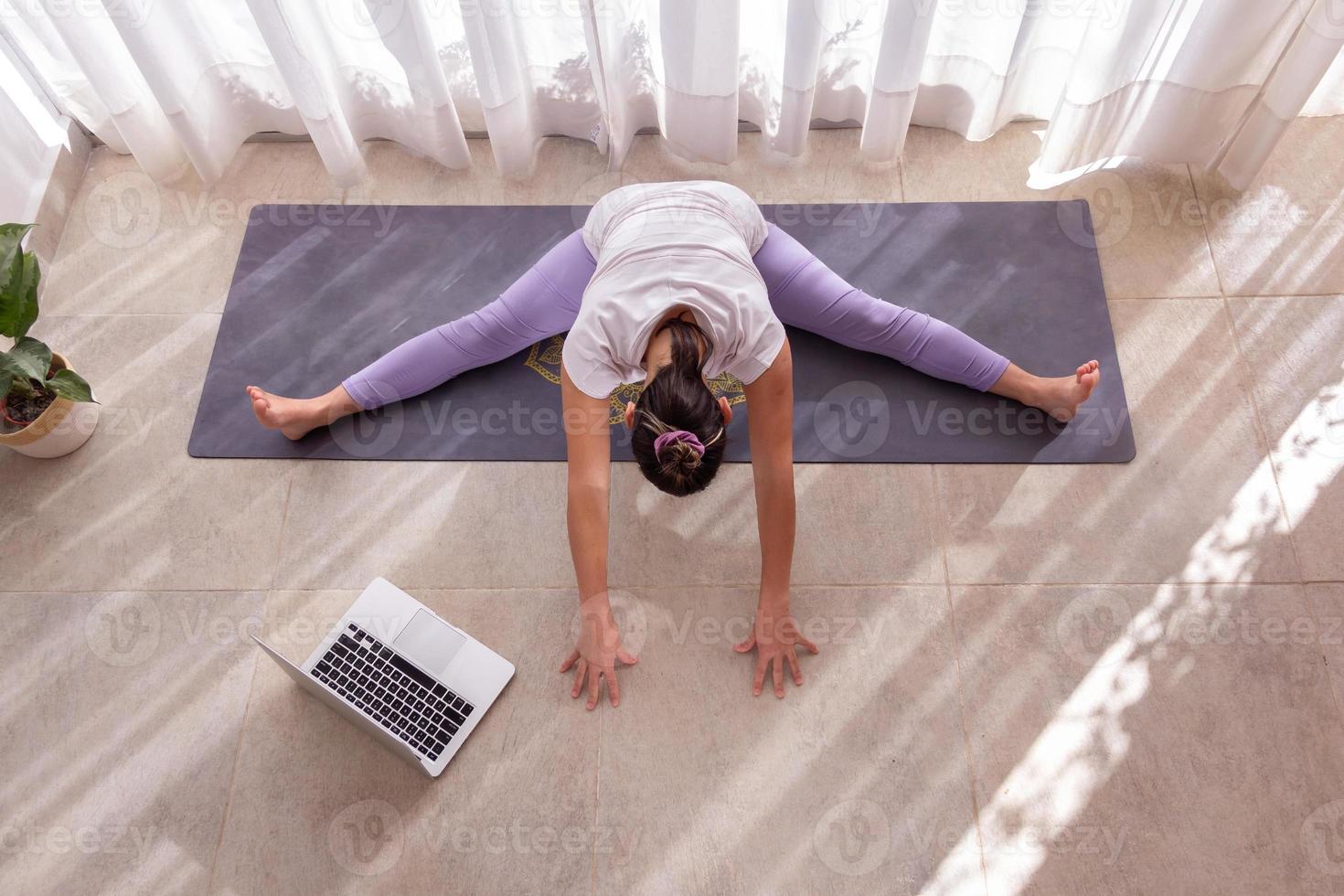 Young woman practices yoga class online photo