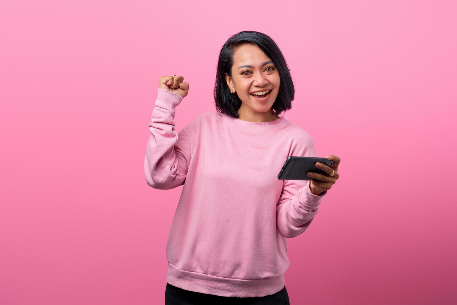 Young asian woman excited and happy playing video games on smartphone photo