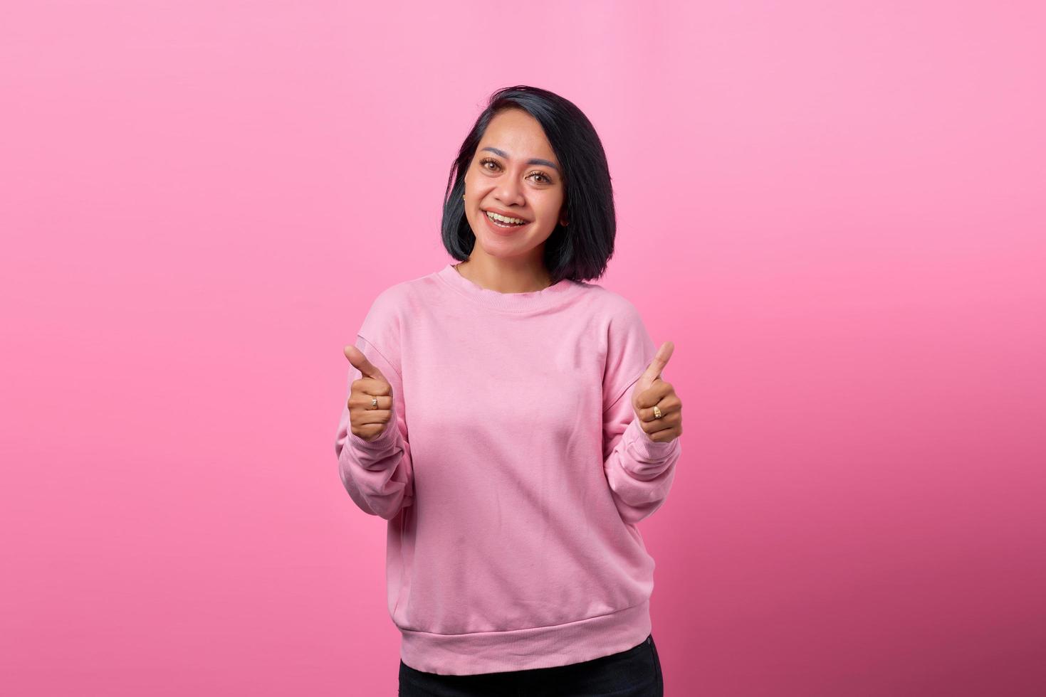 Hermosa mujer asiática sonriendo y mostrando dos pulgares hacia arriba foto