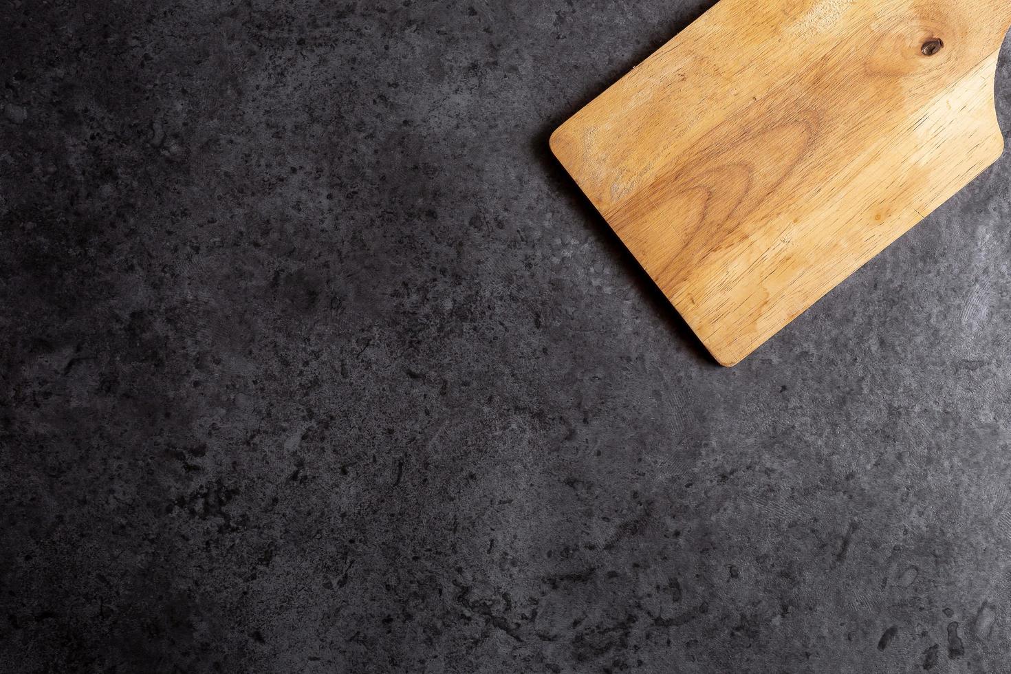 Tabla de cortar de madera sobre fondo de mesa negro foto