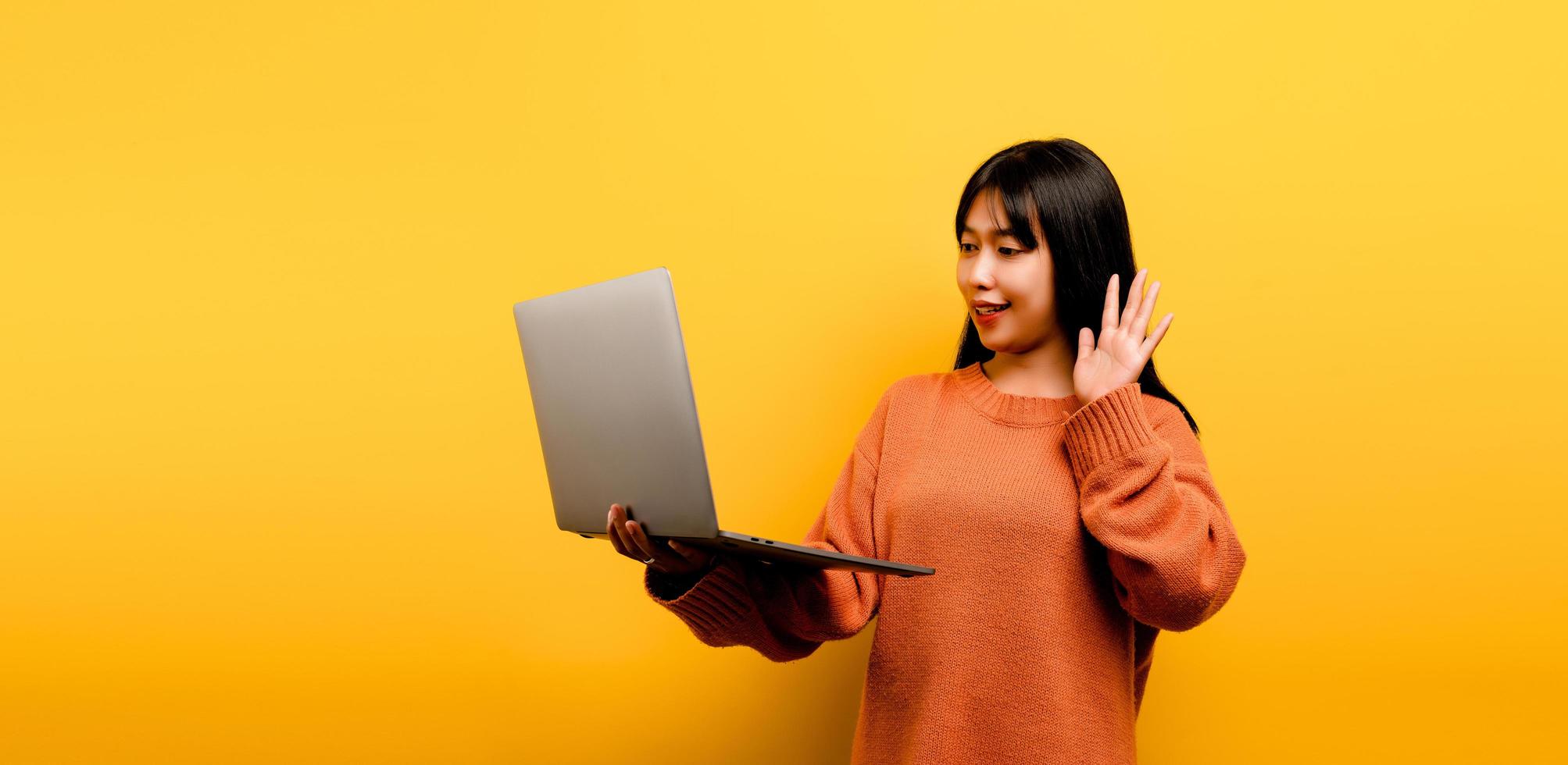 Concepto de comunicación en línea chica asiática usa portátil en casa amarillo foto