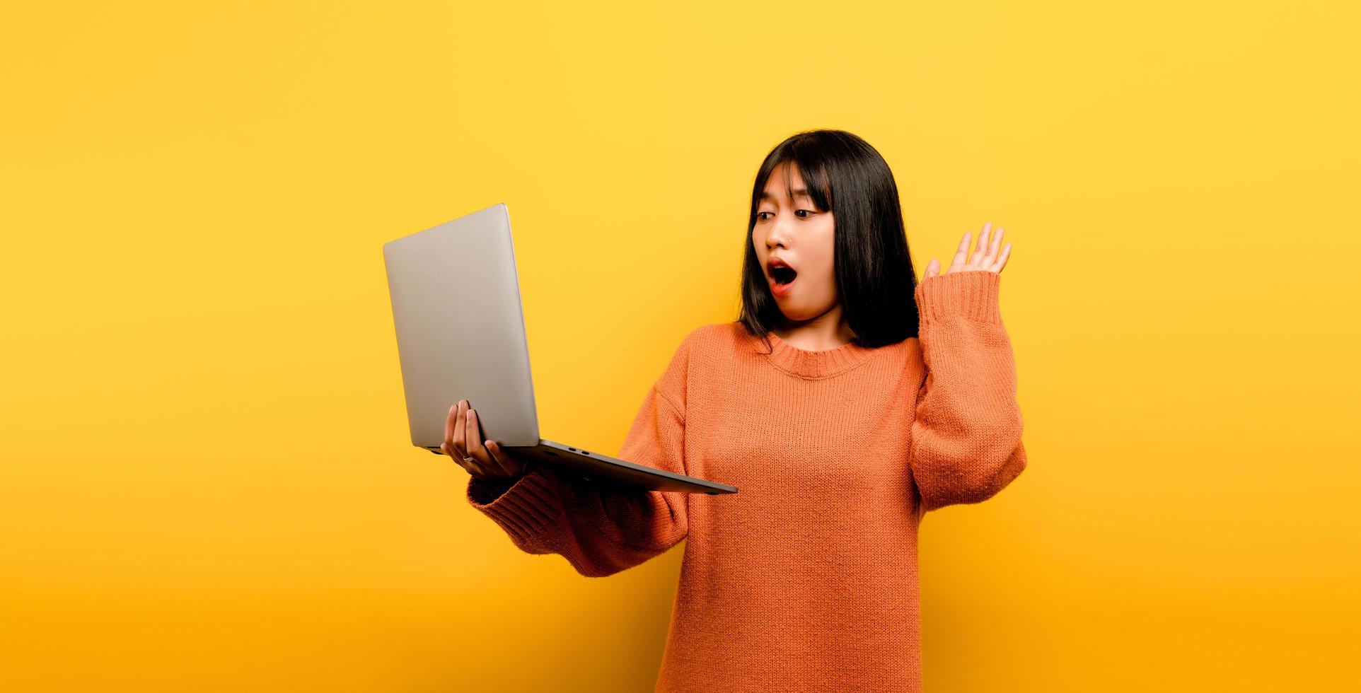 Online communication concept asian girl use laptop at home yellow photo