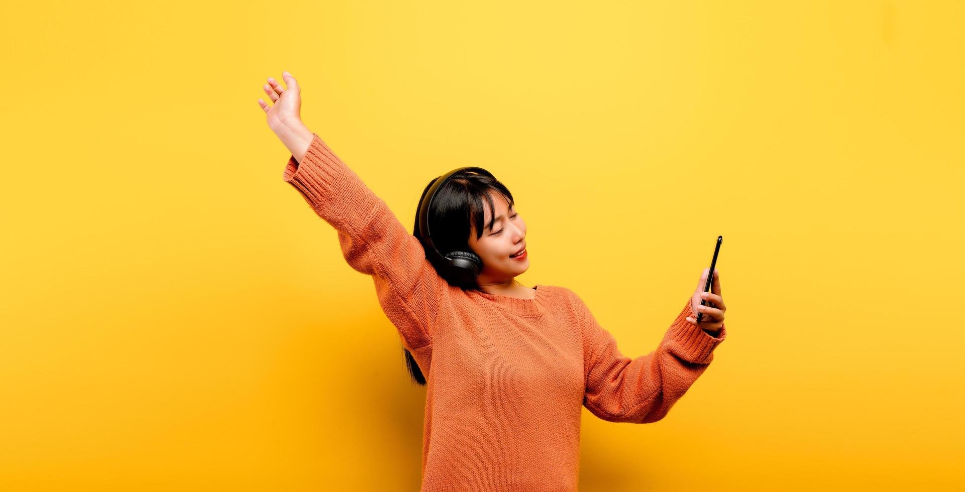 Asian woman happily using the phone and listening to music photo