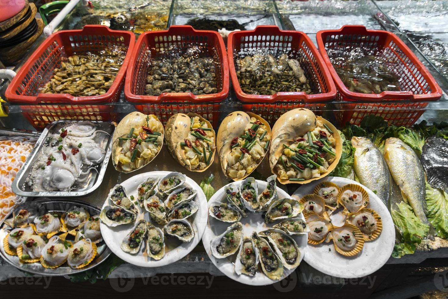 Mezcla de mariscos frescos gourmet en exhibición en el mercado callejero de Xiamen, China foto
