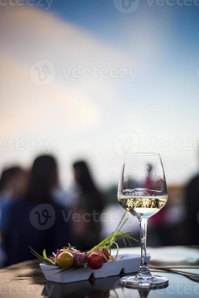 Copa de vino blanco con bocadillos de tapa de comida gourmet en el bar al aire libre al atardecer foto