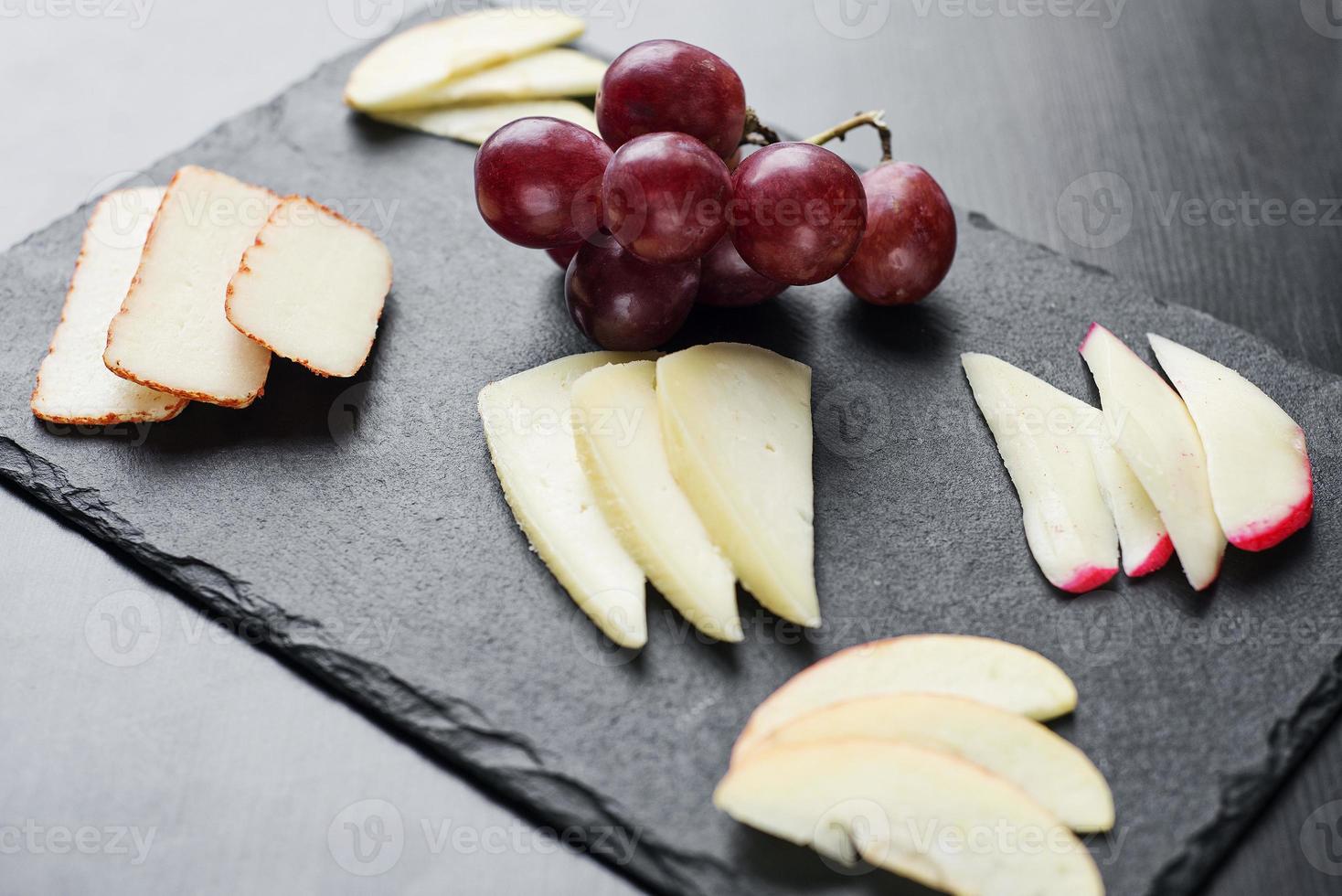Gourmet mixed cheese board tapas starter with apple and grapes snack photo