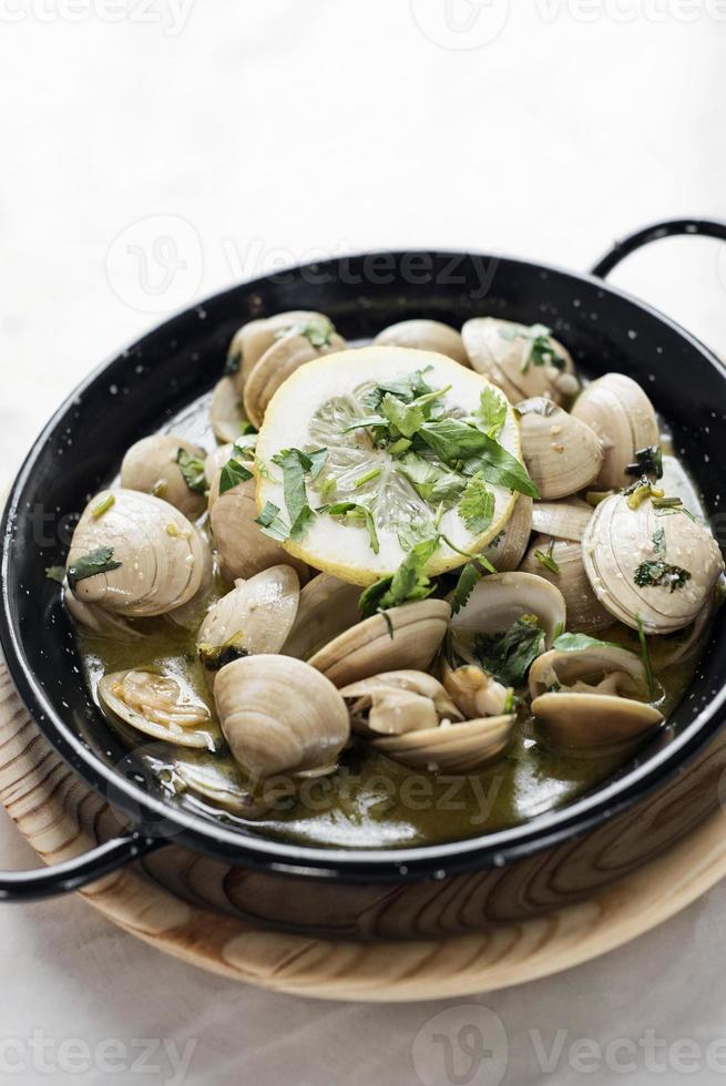 almejas guisadas al ajillo y salsa de marisco al vino blanco foto