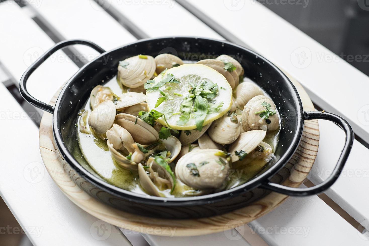 Almejas guisadas portuguesas al ajillo y salsa de marisco al vino blanco foto