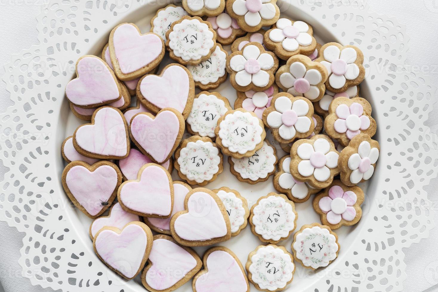 Galletas de galleta glaseadas rosadas y blancas mezcladas en bandeja foto