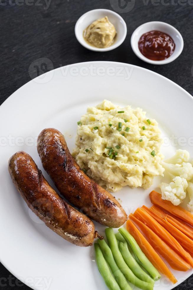 Salchicha alemana con puré de patatas y verduras comida sencilla foto