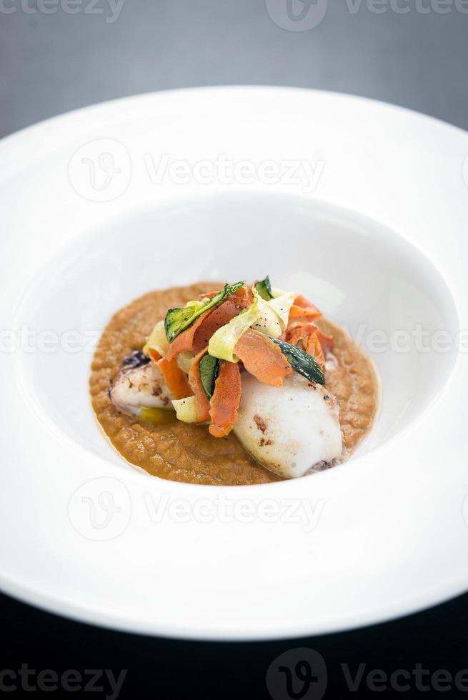 Gourmet fusion cuisine stuffed squid with Asian pickled vegetables in pumpkin curry sauce photo