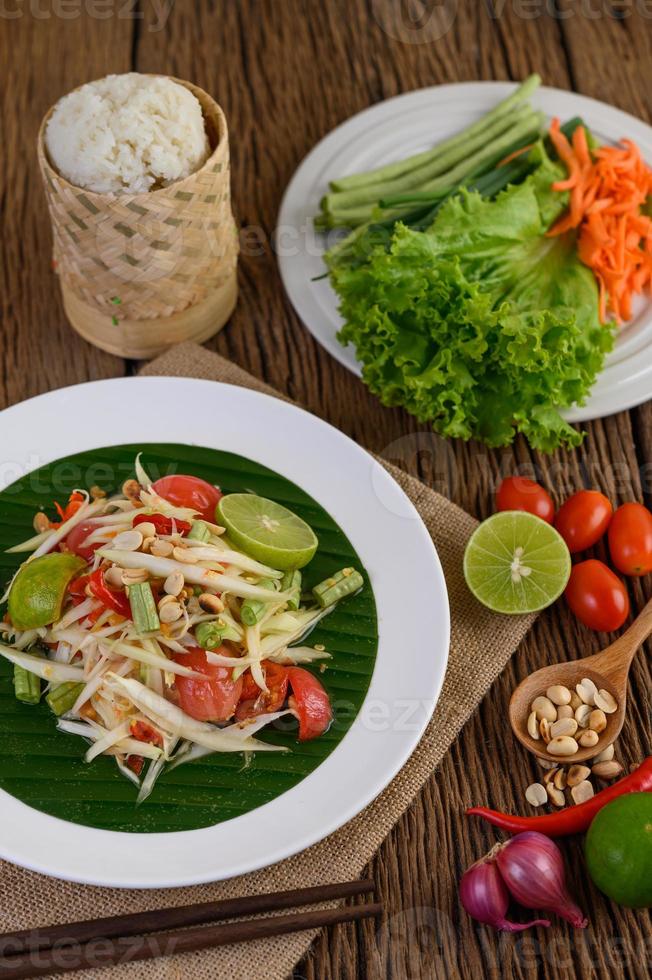 Ensalada de papaya en un plato blanco sobre una mesa de madera foto