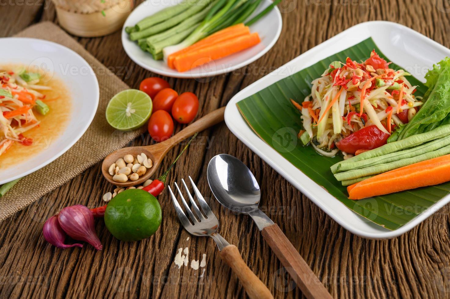 Ensalada de papaya en un plato blanco sobre una mesa de madera foto