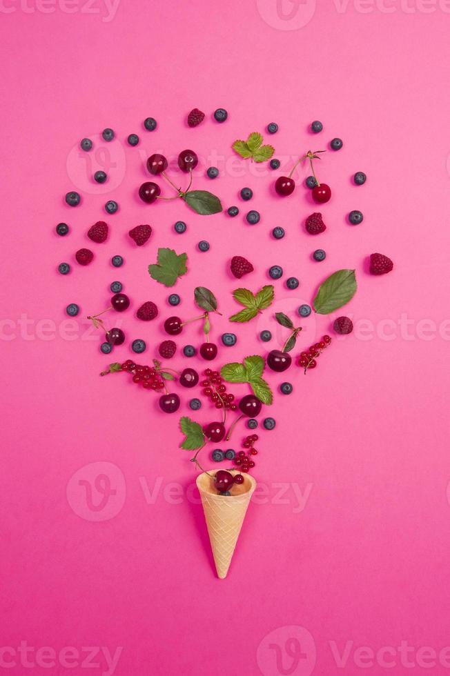 cereza fresca con cono de galleta sobre fondo rosa. concepto de diseño. foto