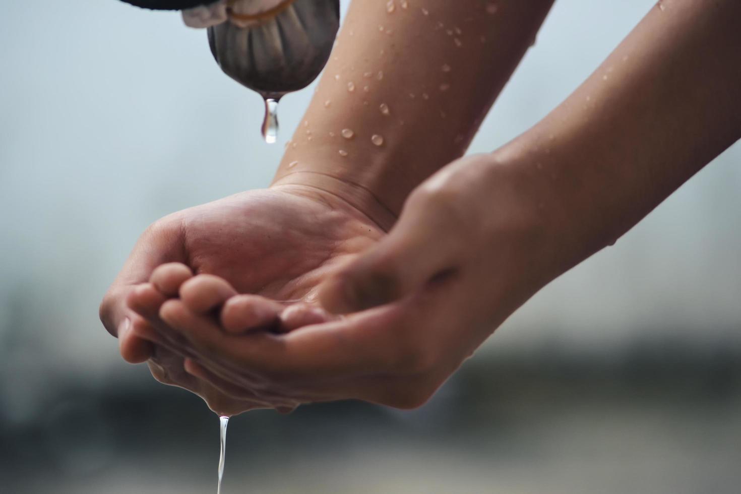 Hand catches water drops coming out of faucet photo