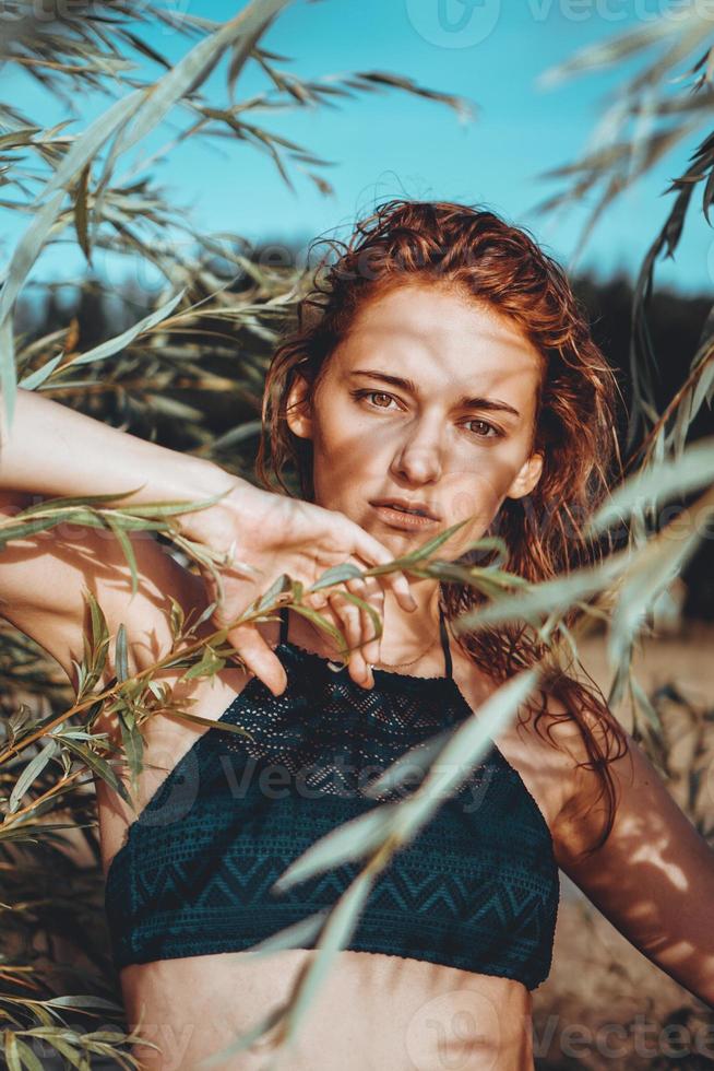 Woman in bikini on a tropical beach with plants photo