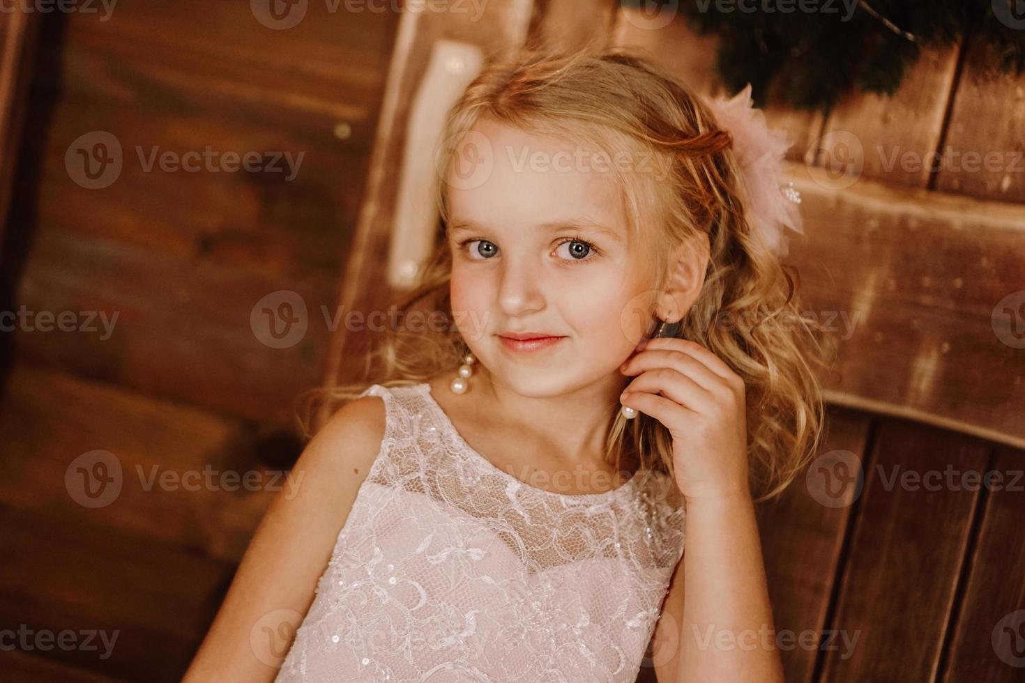 Chica con aretes de pelo largo y rubio en vestido rosa foto