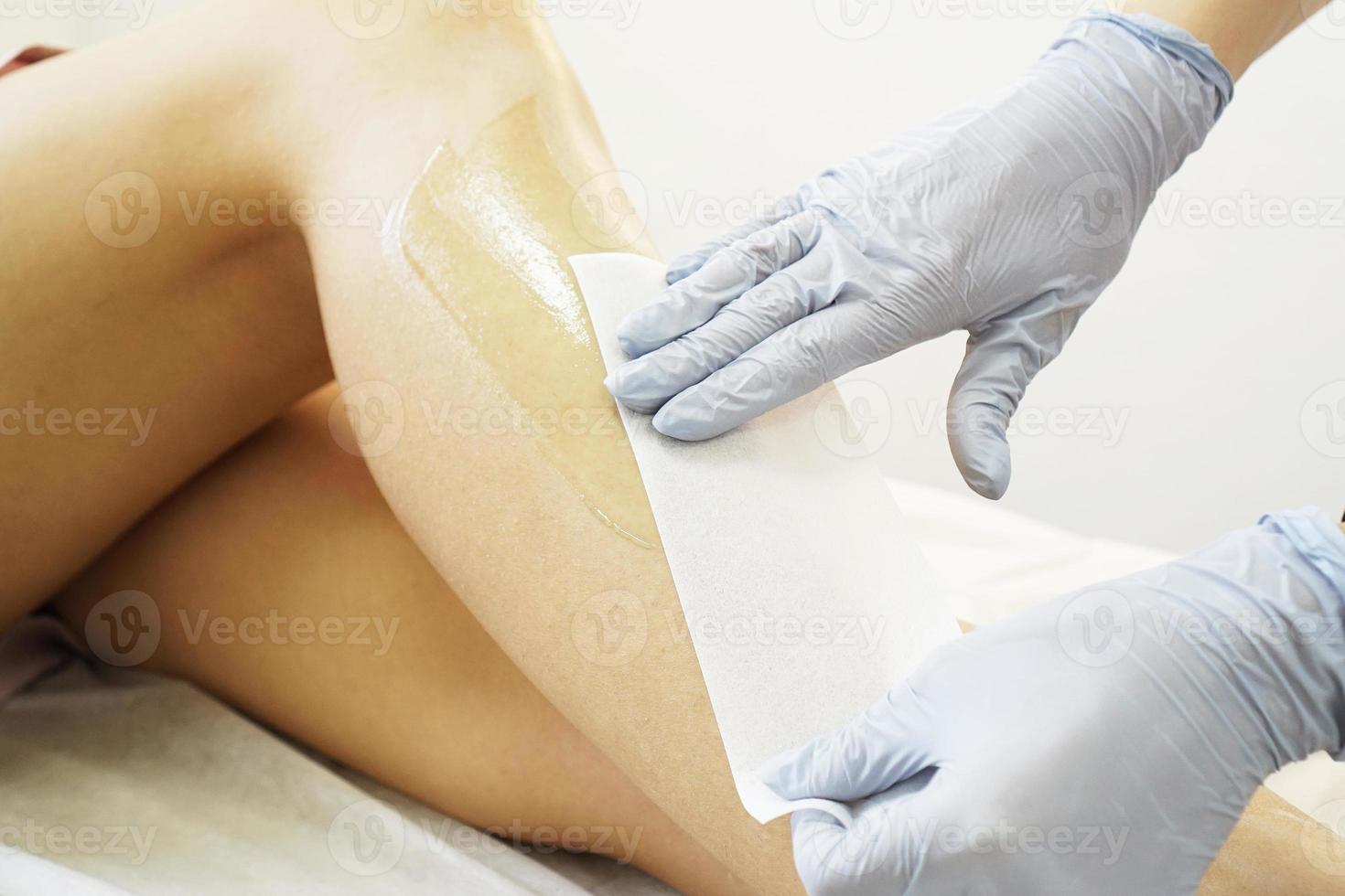 Hair removal from beautiful female legs. Waxing in a beauty salon photo