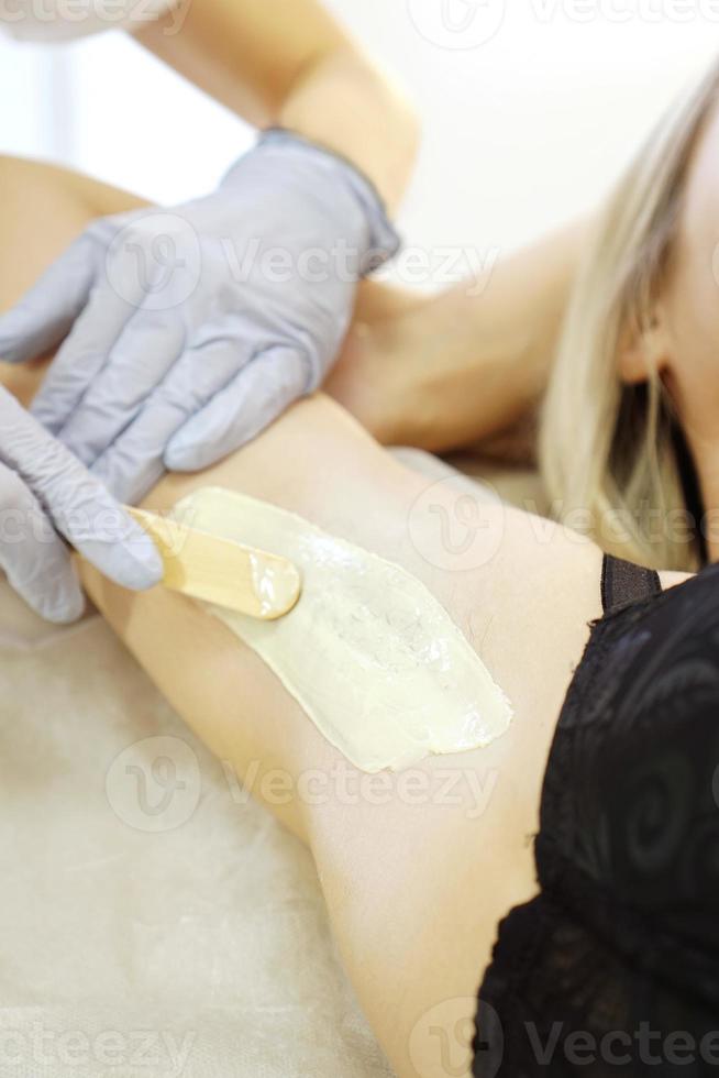 Waxing woman armpit with spatula. Salon wax beautician epilation photo