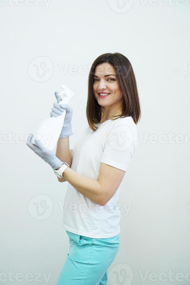 Mujer sostiene una botella de spray - antiséptico o detergente como pistolas foto