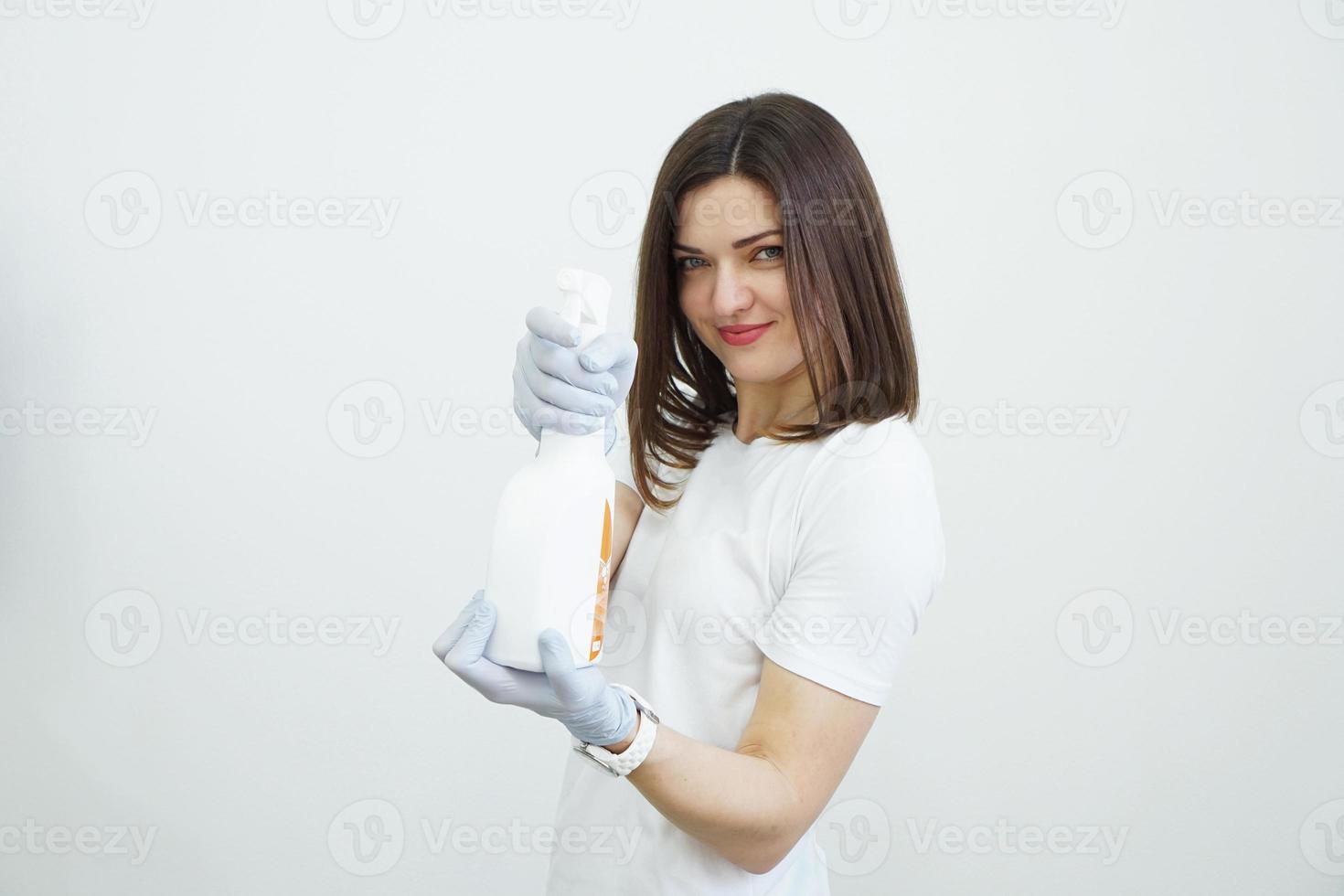 Woman holds spray bottle - antiseptic or detergent like guns photo