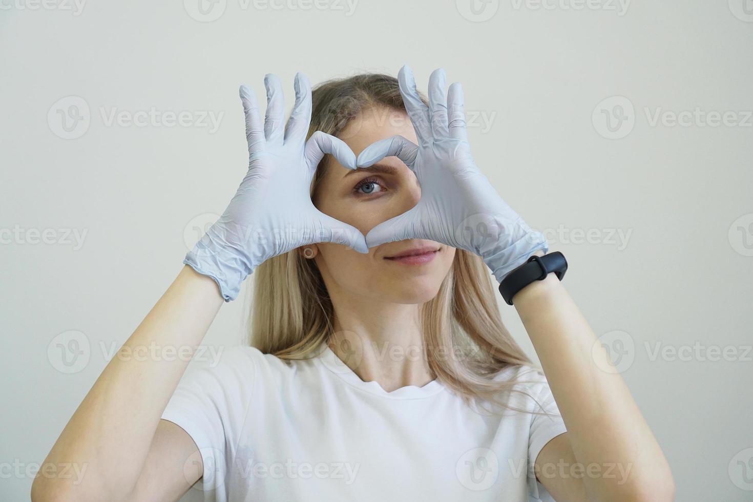 sección de cosmetología depilación. las manos en los guantes hacen un corazón foto