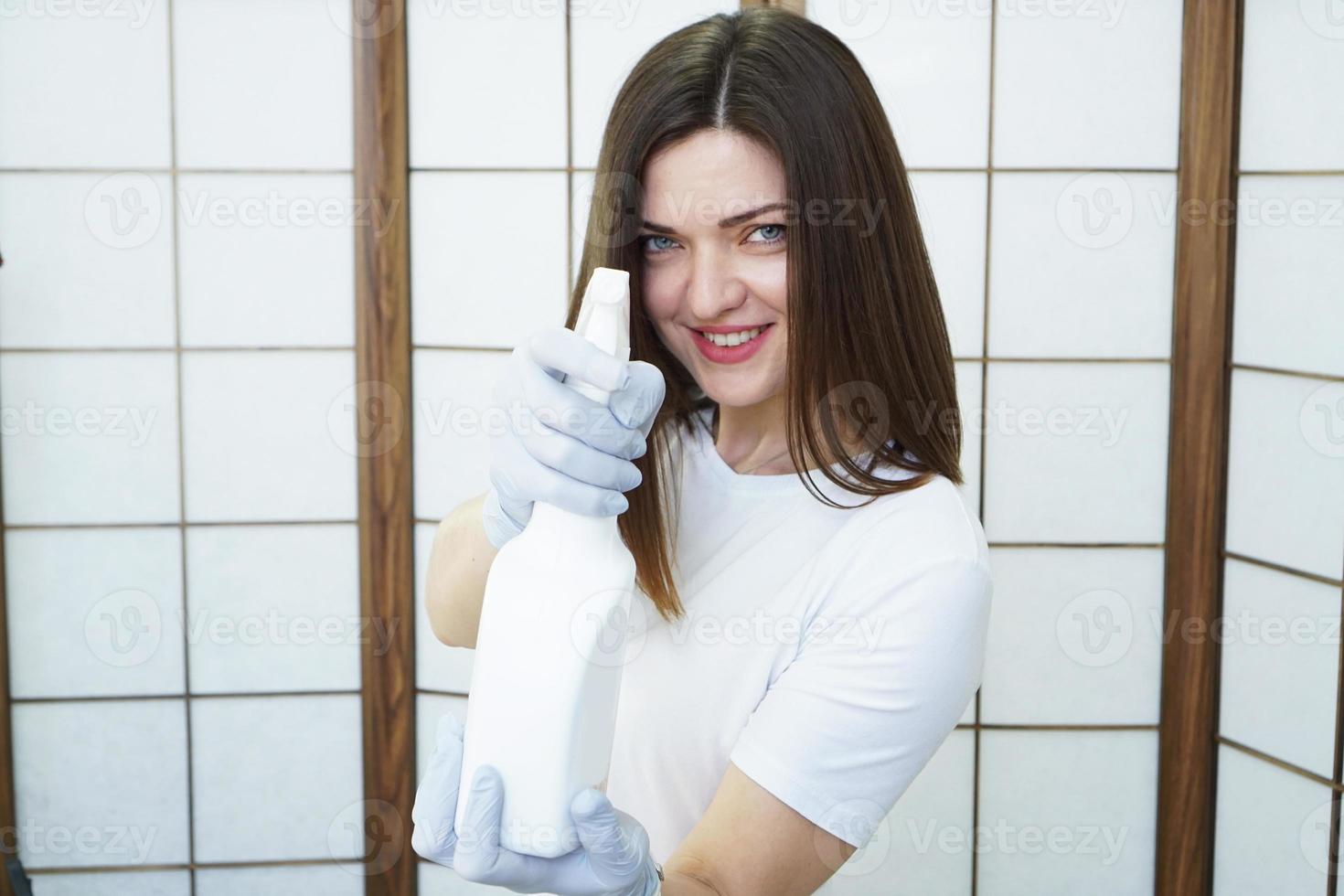 Woman holds spray bottle - antiseptic or detergent like guns photo