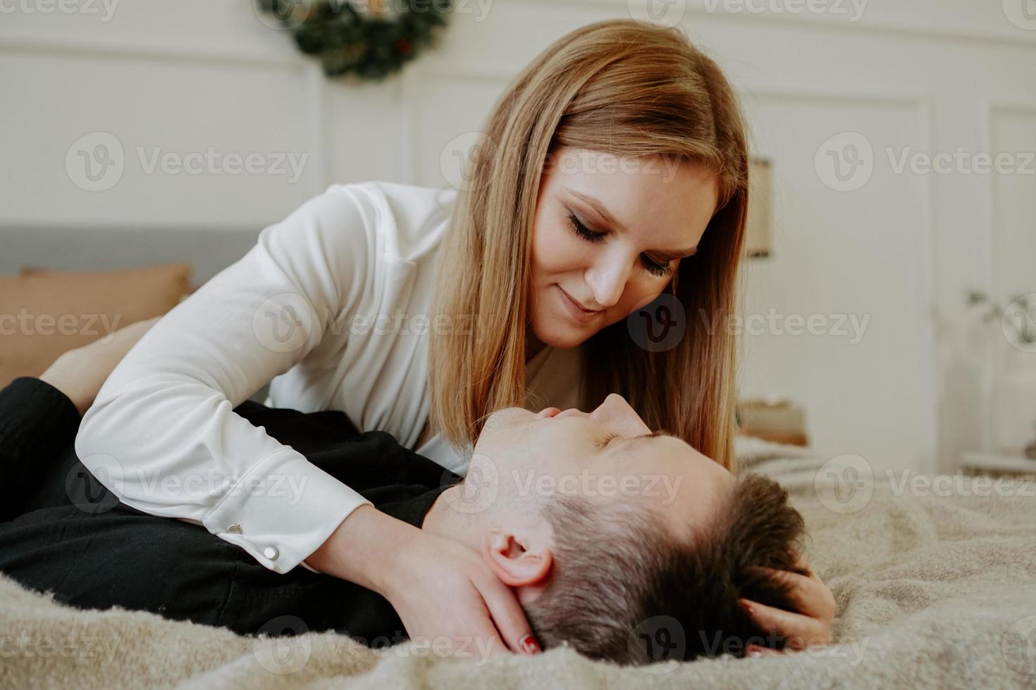 Pretty loving couple in bed together. They are hugging and smiling photo