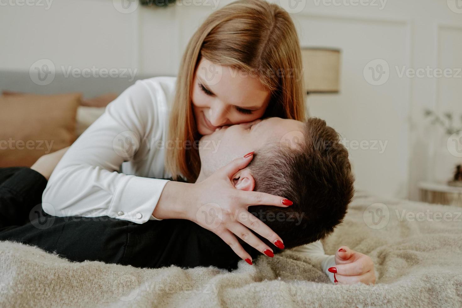 Pretty loving couple in bed together. They are hugging and smiling photo