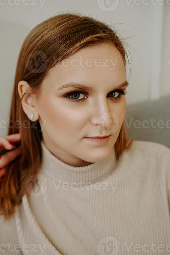 Portrait of Woman dressed in beige sweater sitting on bed photo