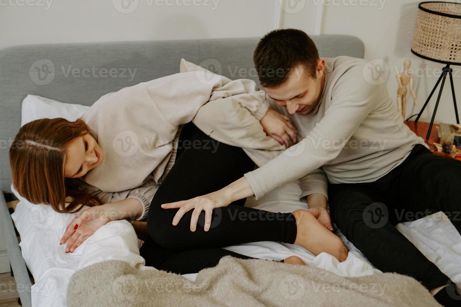 joven pareja enamorada está acostada en la cama, sonriendo y jugando foto