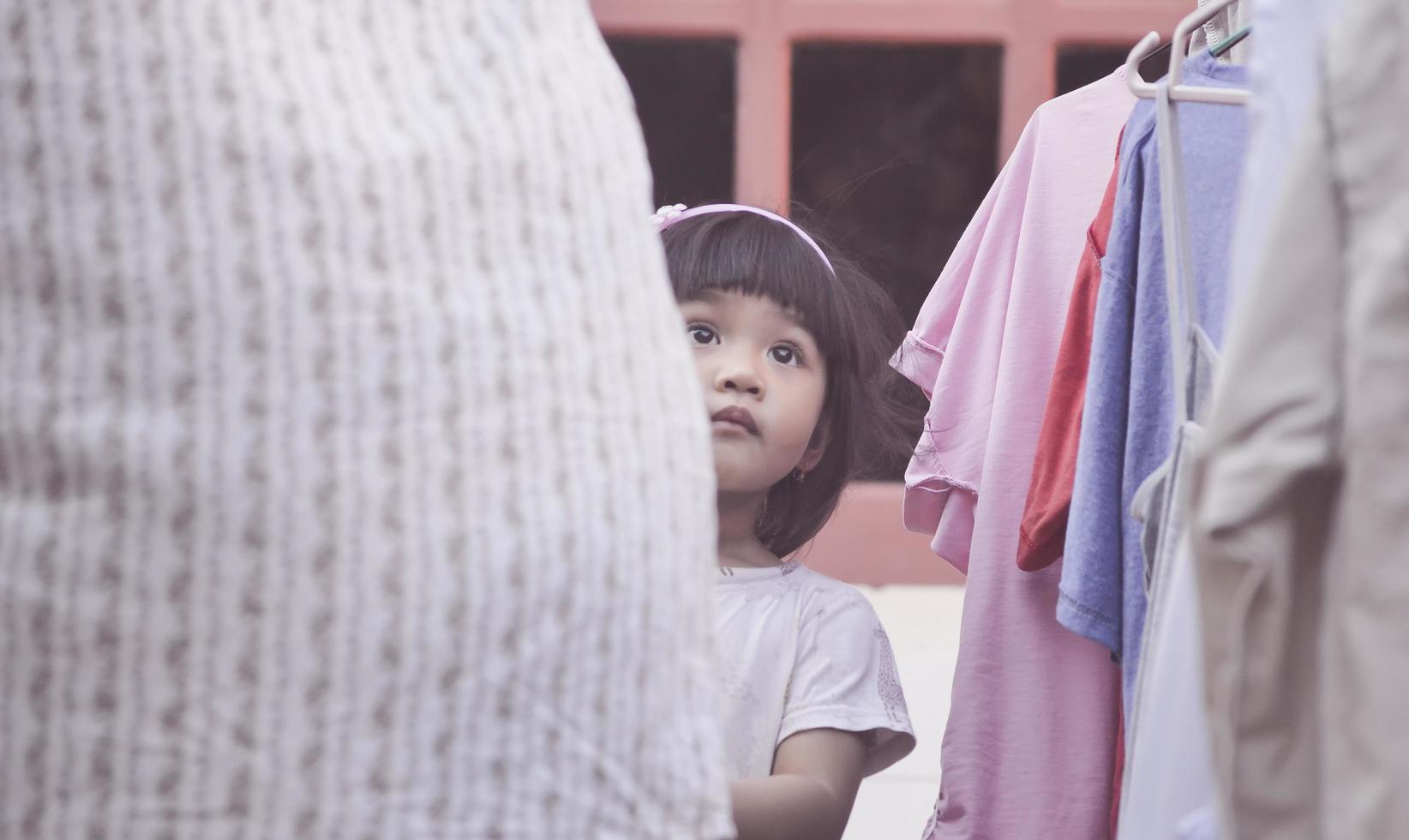 una niña acompaña a su madre a secar la ropa. foto