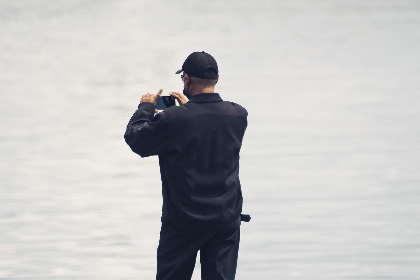 Sorong, Papua Occidental, Indonesia 2021- un hombre tomando una fotografía desde la cubierta de un muelle de madera foto