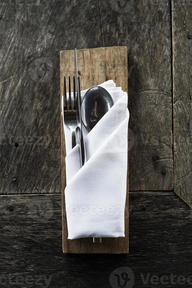 Cubiertos elegantes en una vieja mesa de restaurante informal de madera rústica foto