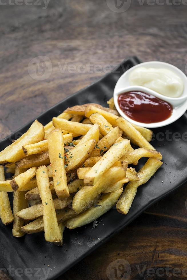 Papas fritas bocadillo lateral con salsas para mojar en la mesa de madera foto