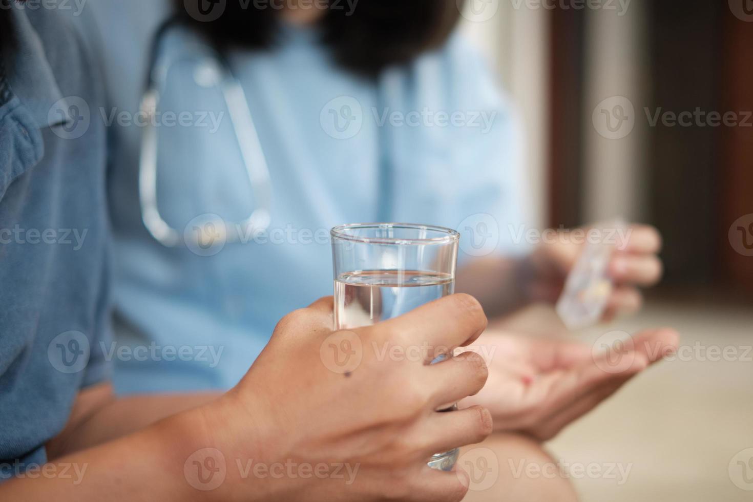 Doctor with drinking glass, help patient takes medicine. photo