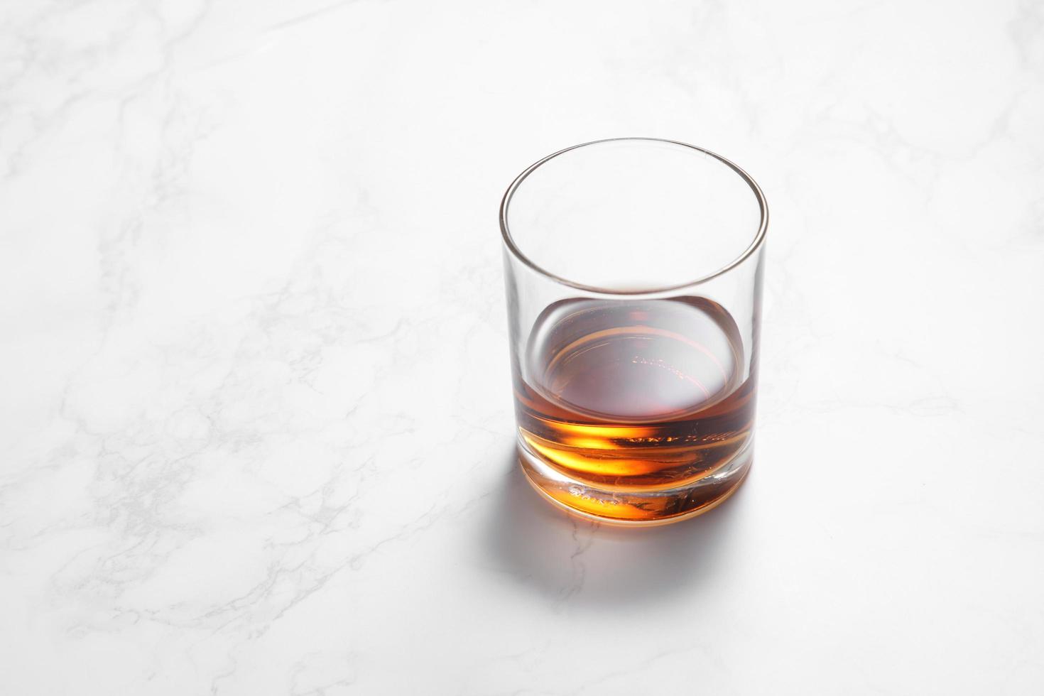 Scotch whiskey in glass on a white marble table photo